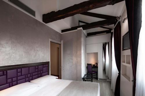 威尼斯帕加内利酒店的一间卧室配有一张大床和紫色床头板