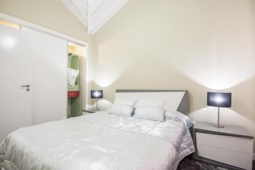 PiedadeCasa Céu D'Abraão的一间卧室配有一张带两盏灯的大型白色床。