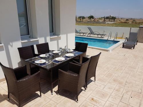 拉纳卡T&E Villa的餐桌和椅子以及游泳池