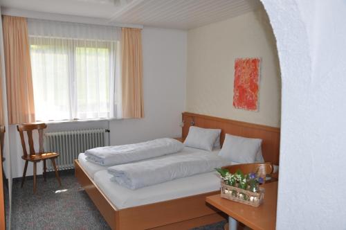 阿尔贝施文德Haus Berchtold的卧室配有1张床、1张桌子和1把椅子