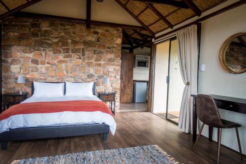 帕特森Ikwanitsha Lodge的一间卧室设有一张床和石墙