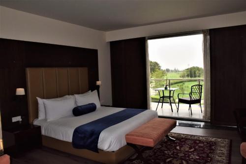 拉合尔Defence Raya Golf & Country Club的一间卧室配有一张床,阳台配有桌子