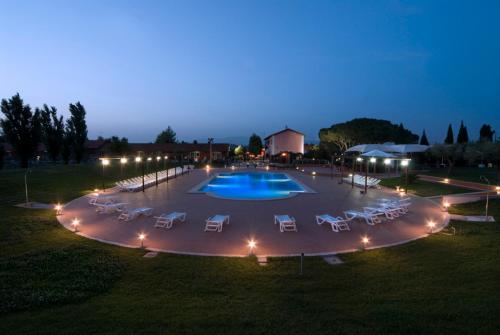 拉蒂纳Il Casale Corte Rossa的一座大型游泳池,晚上在游泳池周围摆放躺椅