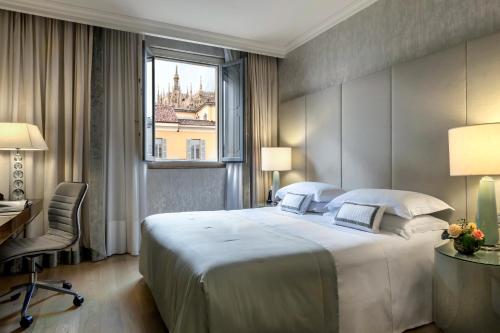 米兰米兰罗莎格兰德 - 星际连锁酒店的一间卧室配有一张大床、一张书桌和一个窗户。