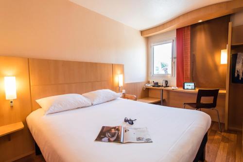 马恩河畔埃索姆蒂耶里堡宜必思酒店的一间酒店客房,配有一张带杂志的床