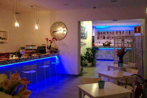 切塞纳蒂科马雷意酒店的一间带桌子的餐厅和一间拥有蓝色灯光的酒吧