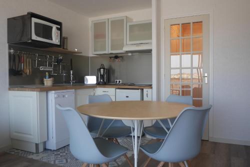 马翁普拉日堡La Timonerie - La Caraque 35, vue mer et dunes classé 2 étoiles的厨房配有木桌和蓝色椅子