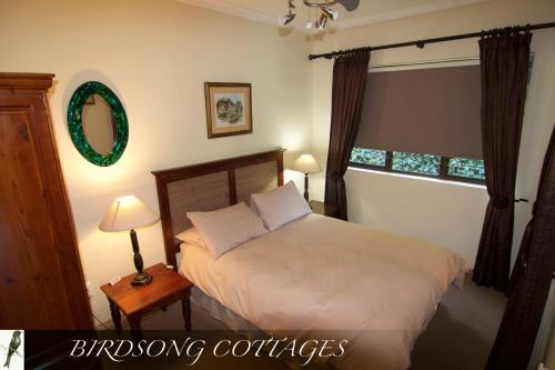 香槟谷Birdsong Cottages的一间卧室配有一张床、两盏灯和一面镜子