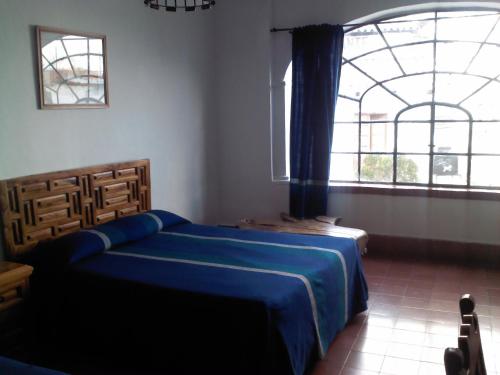 塔斯科·德·阿拉尔孔圣普里斯卡酒店的一间卧室设有蓝色的床和大窗户