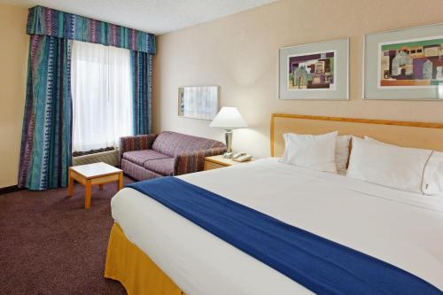 圣安东尼奥圣安东尼奥河心区智选假日套房酒店的酒店客房带一张大床和一把椅子
