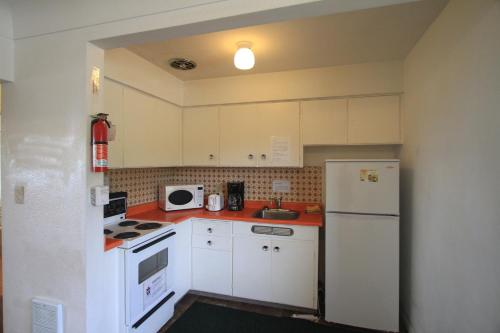 艾伯尼港日落汽车旅馆的厨房配有白色橱柜和白色冰箱。