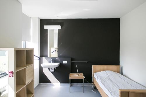 EverbeekDe Kleppe的一间卧室设有黑色墙壁、水槽和一张床
