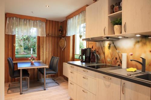 诺伊豪森Ferienhaus Erzgebirge "An der Trebe" mit Kamin und Sauna的厨房配有水槽和桌椅