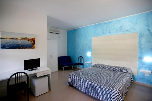 维耶斯泰Hotel Parco Carabella partner Elite Hotels的一间卧室配有一张床、一张书桌和一台电视。