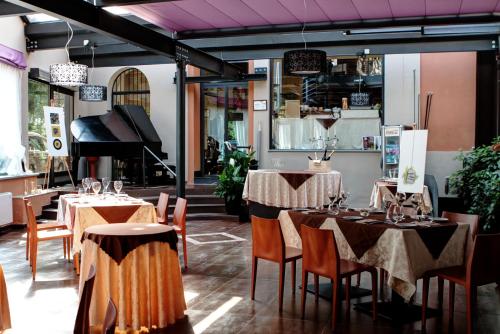 都灵德伊皮托利酒店的一间带桌椅和钢琴的餐厅