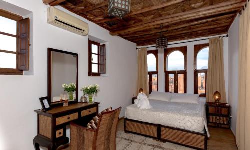 马拉喀什摩达摩洛哥传统庭院住宅的卧室配有一张床、一张书桌和窗户。