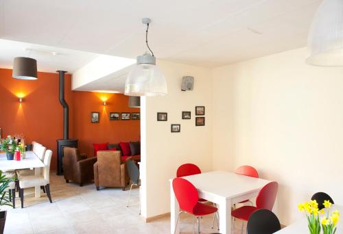 鲁汶鲁汶城市旅舍的一间用餐室,配有红色的椅子和白色的桌子