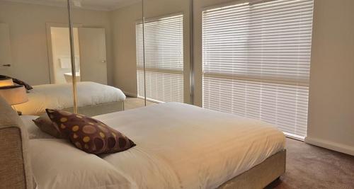 卡那封The Carnarvon Luxury Canal Home的一间卧室设有两张床和大窗户