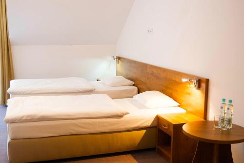 德罗希琴Hotel Drohicki的酒店客房设有两张床和一张桌子。