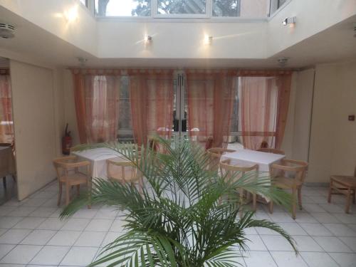 伊维特河畔吉夫乐维雷治酒店的一间设有桌椅的餐厅,并种植了棕榈树