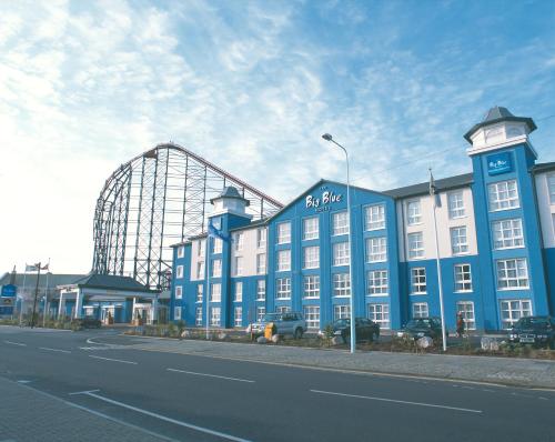 布莱克浦大蓝酒店 - 黑池游乐海滩（Blackpool Pleasure Beach）的一座蓝色的大建筑,后面有过山车