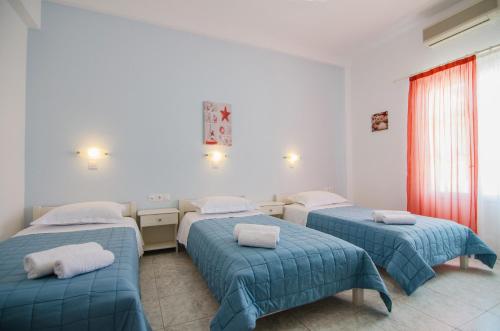 伊奥斯乔拉Athena Rooms的配有蓝色棉被的房间的三张床
