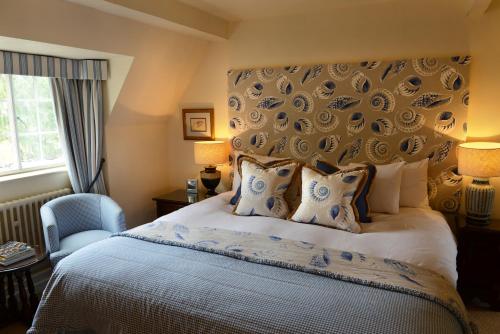 莫顿因马什庄园酒店的一间卧室配有一张大床和一张蓝色椅子