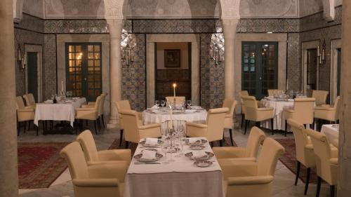 突尼斯Dar El Jeld Hotel and Spa的一间设有白色桌椅和蜡烛的餐厅
