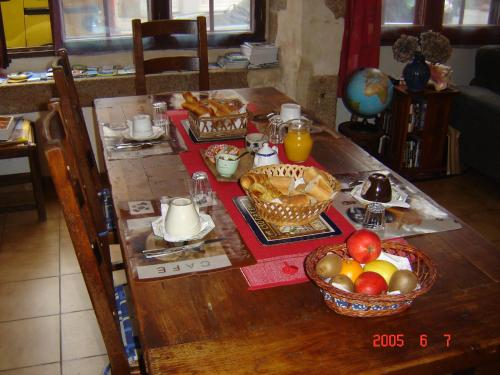 格朗维尔Le Logis du Roc的一张带早餐食品和一碗水果的桌子