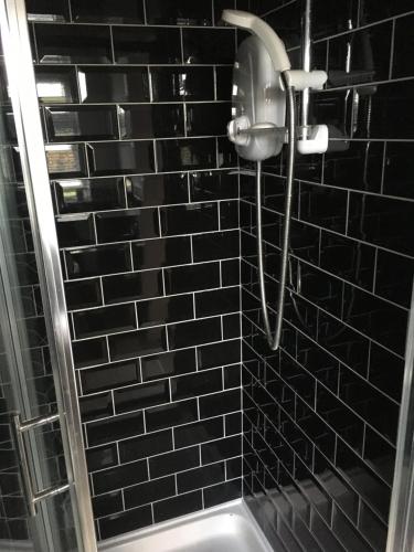 安纳隆Mourne Walks B & B的黑色瓷砖浴室内的淋浴