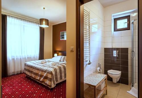 Kochanów可哈诺酒店的一间卧室配有一张床,浴室设有淋浴。