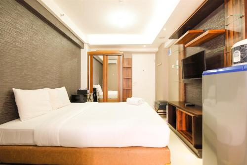雅加达Simple Studio Bassura City Apartment By Travelio的卧室配有白色的床和电视。