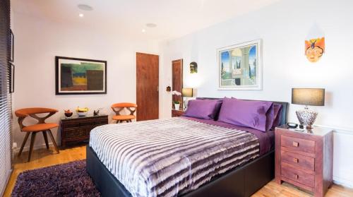 伦敦诺丁山浪漫旅馆的一间卧室配有一张带紫色枕头的大床
