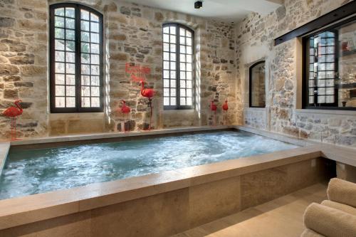 艾格-莫尔特Boutique Hôtel des Remparts & Spa的石墙房间内的热水浴缸