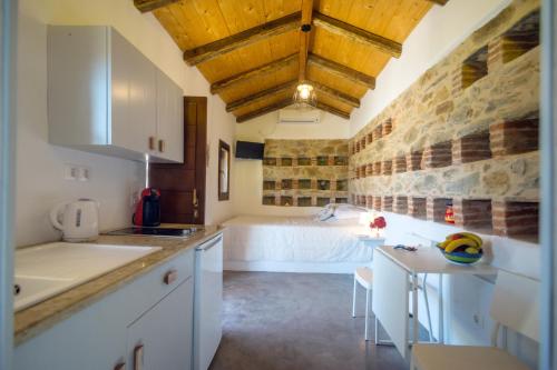 PotamósThe pigeon House的一间厨房,配有白色的橱柜和一张位于客房内的床