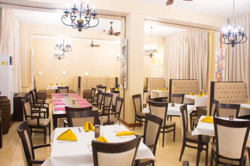 TeshiBest Western Plus Accra Beach Hotel的用餐室配有桌椅和黄色餐巾
