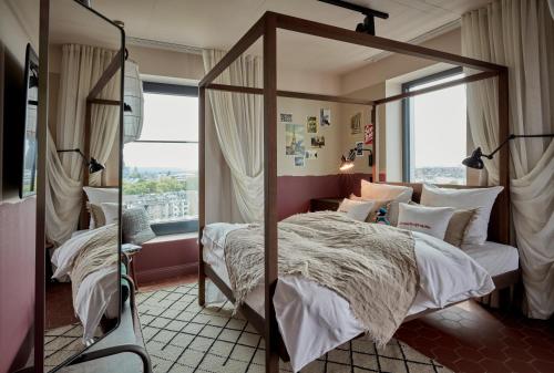 杜塞尔多夫达斯图尔25小时酒店的一间卧室设有一张天蓬床和大窗户