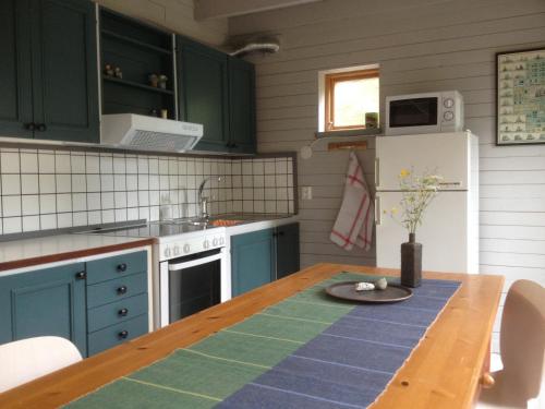 维斯比Brissund的厨房配有绿色橱柜和木桌
