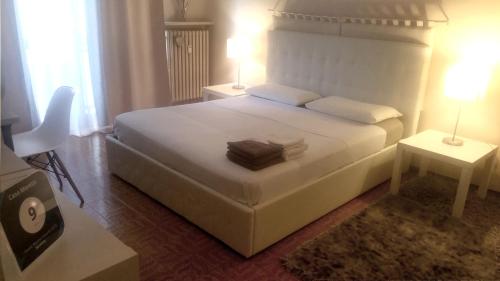 卡萨莱蒙费拉托Casa Moretti的卧室配有一张白色床、两张桌子和两盏灯。
