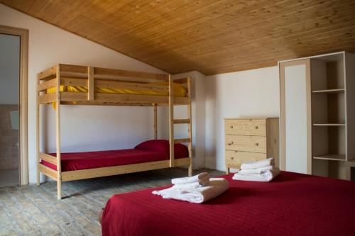 皮斯蒂奇Fontana La Pietra的一间卧室配有两张双层床,铺有红色床单