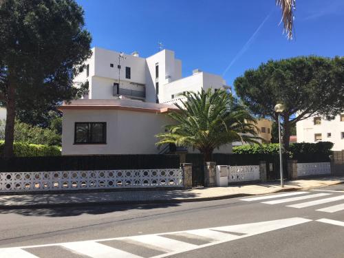 罗萨斯Casa Lorca的街道上一座白色的建筑,有栅栏和树木