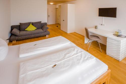 哈德Gästehaus Gritsch的客房设有床、书桌和沙发。