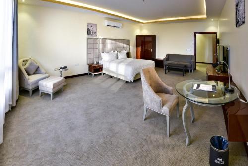 图赖夫Golden Dune Hotel Turaif的酒店客房带一张床、一张桌子和椅子