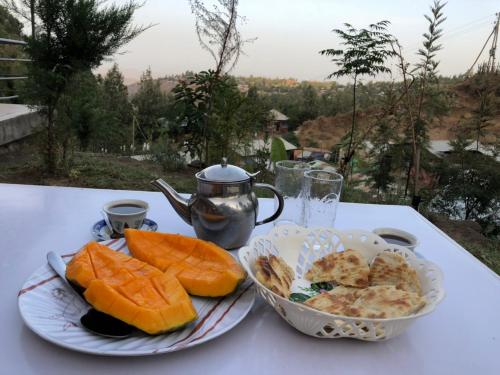 拉利贝拉Mini Lalibela Guest House的一张桌子,上面放着两盘食物和茶壶