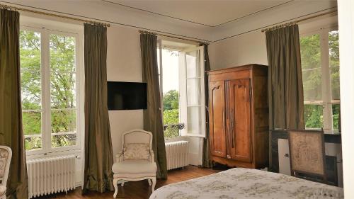 VallenayB&B Château de Preuil的一间卧室配有一张床、一把椅子和窗户。