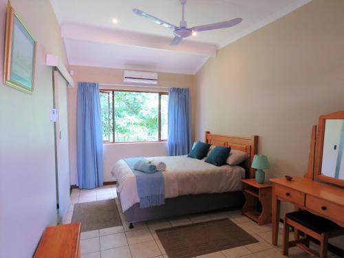 姆通济尼102 Siyayi的一间卧室配有一张带蓝色窗帘的床和一扇窗户