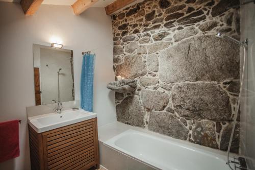 VilacobaO Curralino的浴室配有石墙、浴缸和水槽。