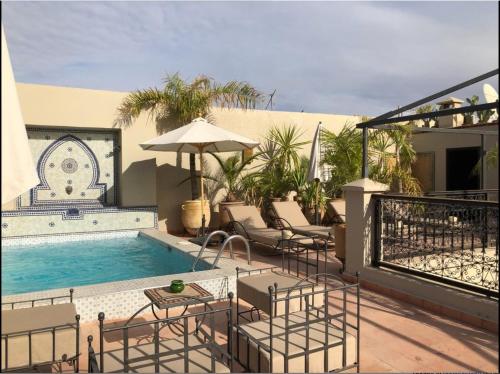 马拉喀什艺术田园庭院旅馆的一个带游泳池、椅子和遮阳伞的庭院