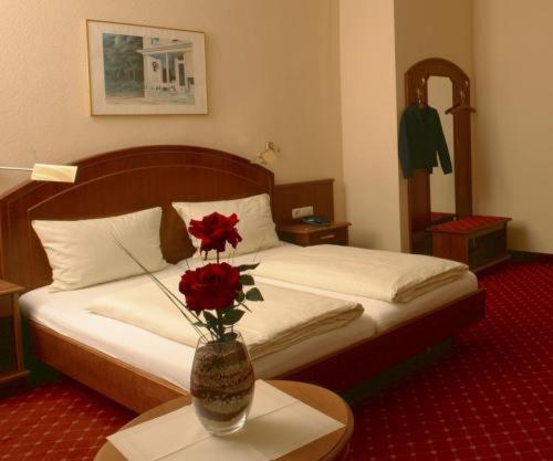 巴登-巴登施韦策霍夫高级酒店的一间卧室,配有一张带花瓶的床铺,桌子上放着鲜花