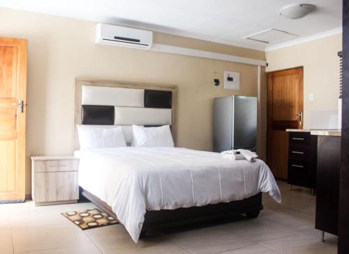 UlundiMbopha Guest House的卧室配有一张白色大床和一台冰箱